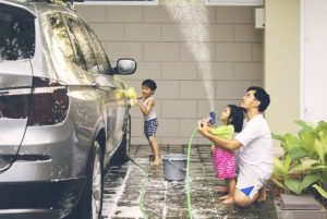 Father washing car with his children
