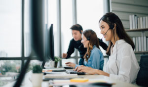 Customer service representative with headset working on computer and smiling